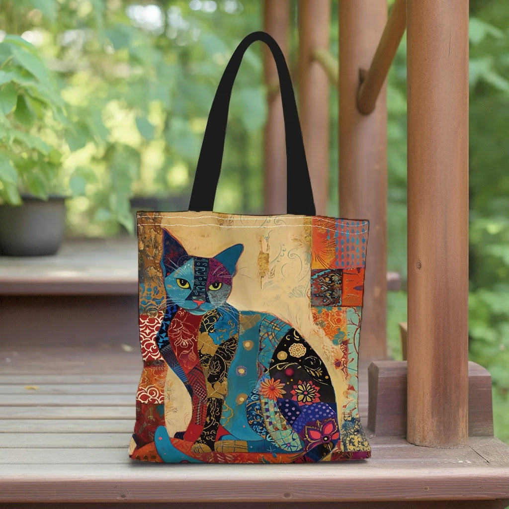 A canvas tote bag featuring a colorful, stylized floral cat design in blues, oranges, and reds, resting on a wooden surface.