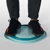 A pair of legs and feet wearing black pants and black shoes standing over a light blue wash basin.