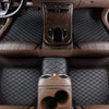 Interior view of a car with premium brown quilted leather floor mats and steering wheel.