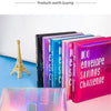 A stack of colorful budget binders with envelopes and a savings challenge theme displayed on a pink surface.