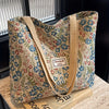 A beige corduroy tote bag featuring a floral pattern with blue and green accents, resting on a light surface.