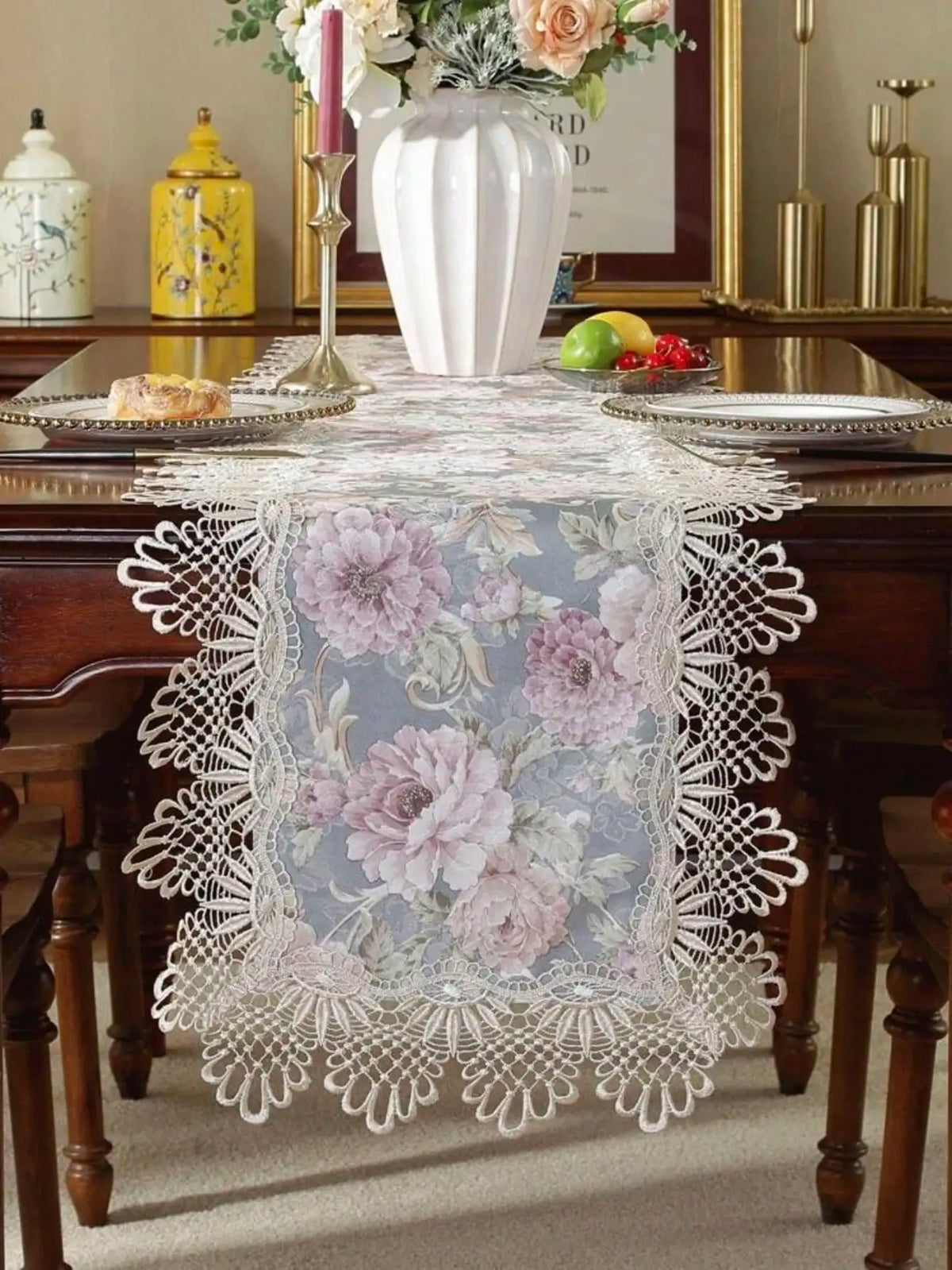 A white lace table runner with a floral pattern is displayed on a dark wooden table.
