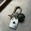 Silver keychain charm featuring a red dice, a heart, and a D-shaped buckle.