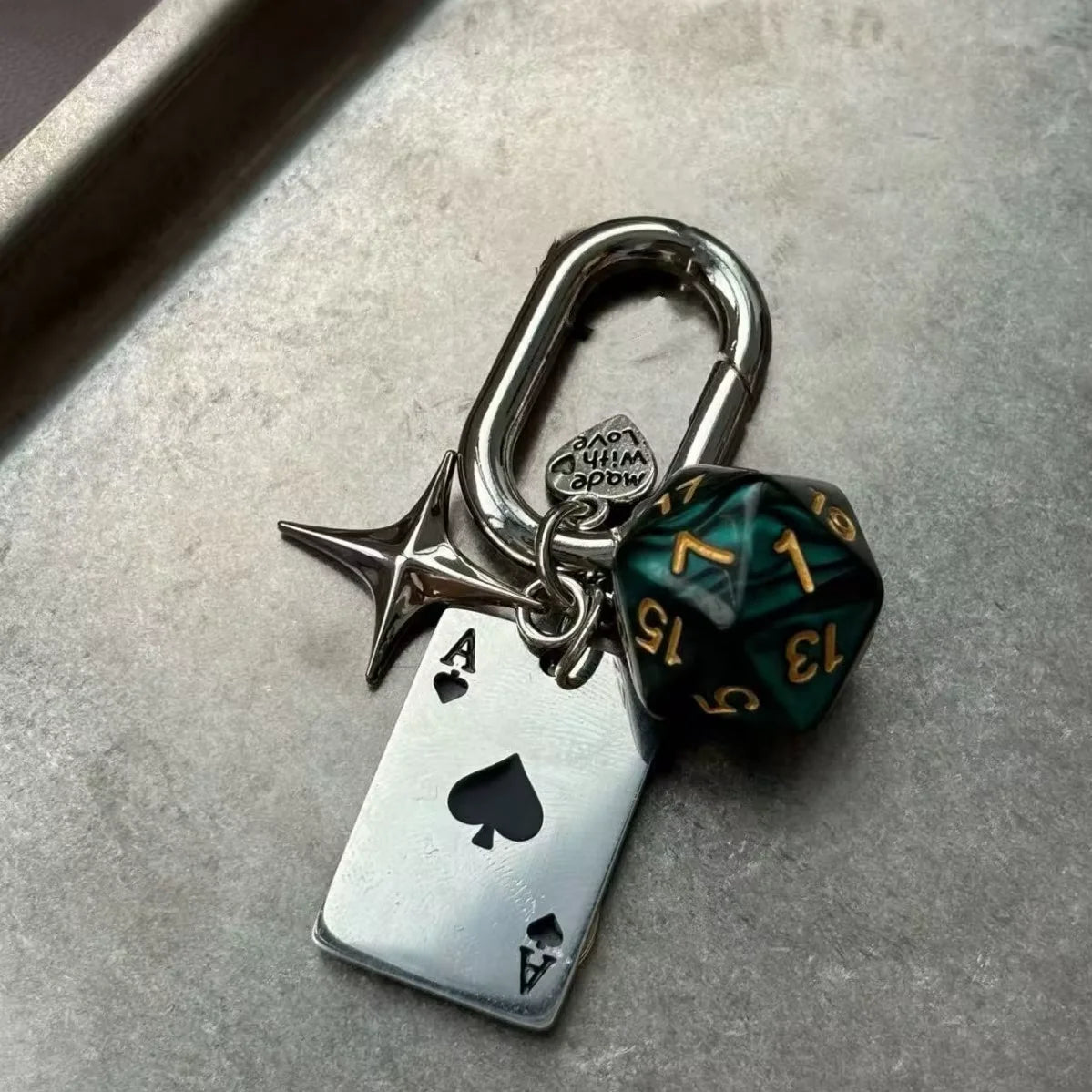 Silver keychain charm featuring a red dice, a heart, and a D-shaped buckle.