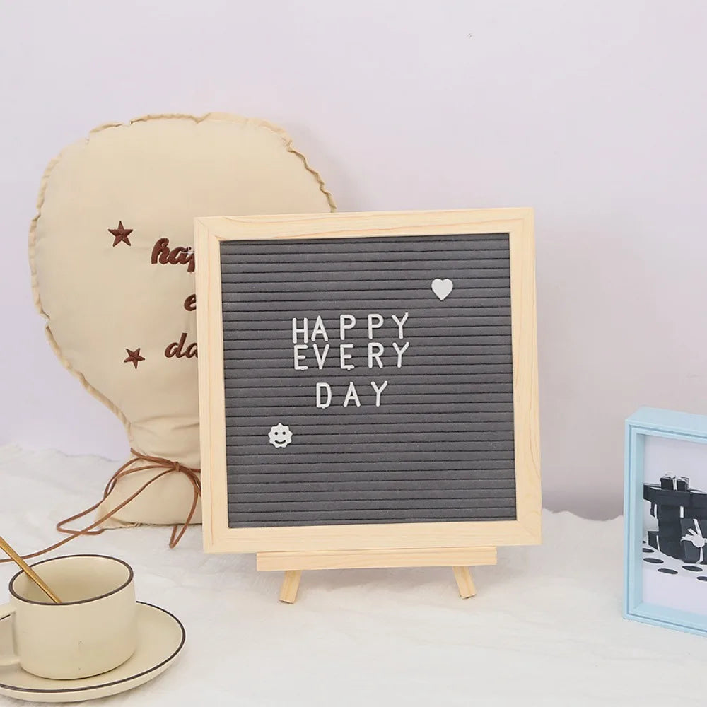 Tablero de fieltro con marco de madera que muestra el texto 'HAPPY EVERY DAY' y un símbolo de corazón.