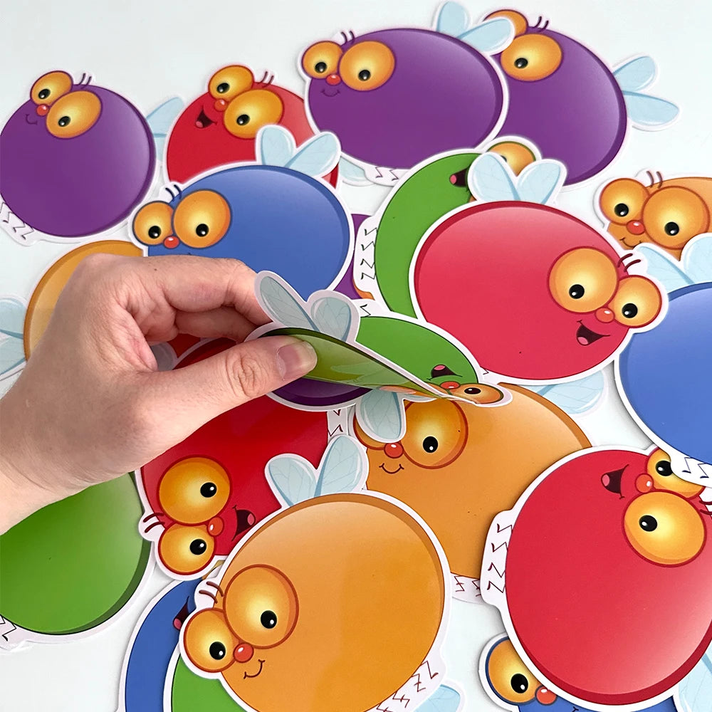 A hand is holding and arranging colorful dry erase fly swat game cards for kids.