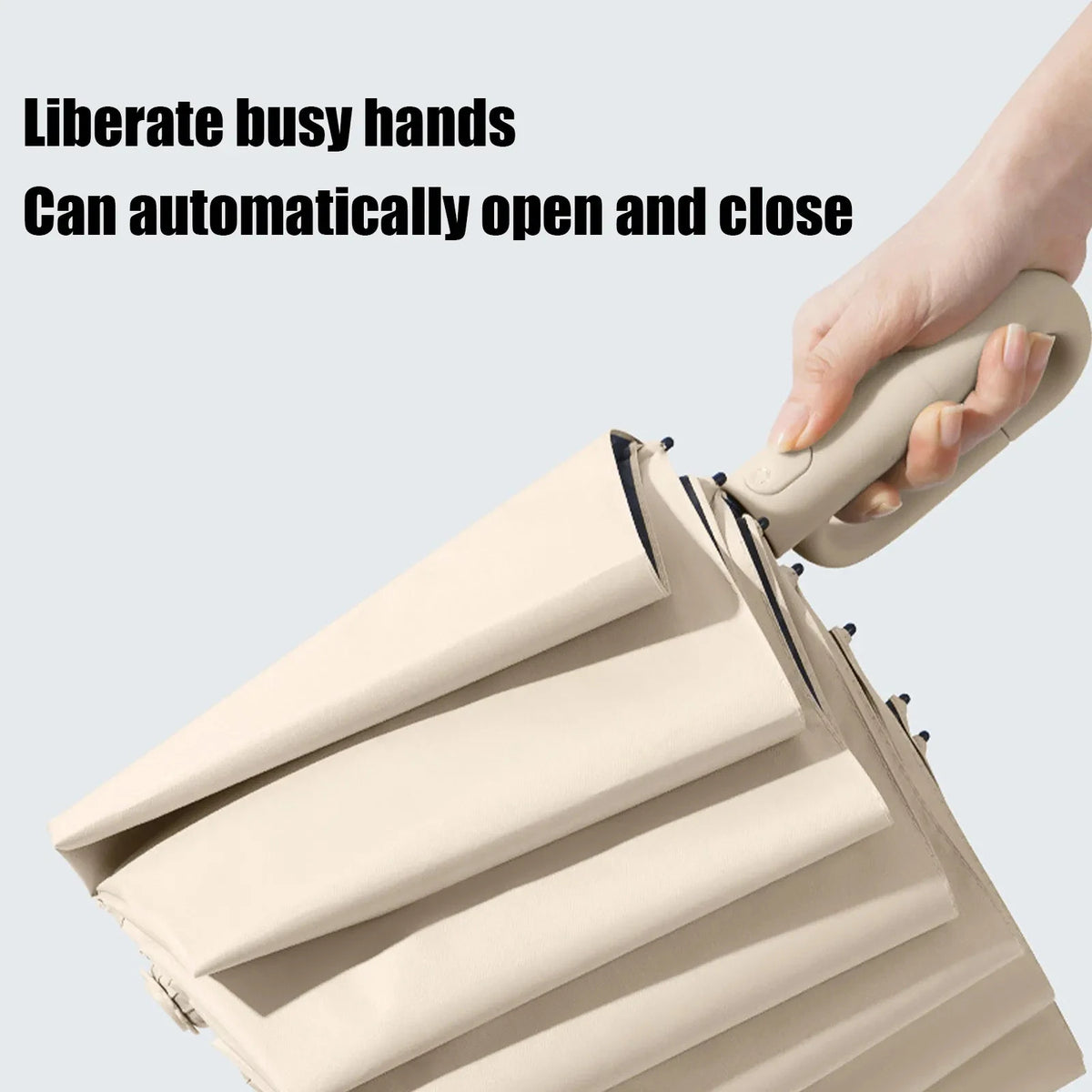 A hand is opening and closing a beige windproof automatic folding umbrella.