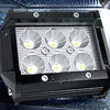 A black LED flood light pod with four circular light elements is mounted inside a vehicle's light bar housing.