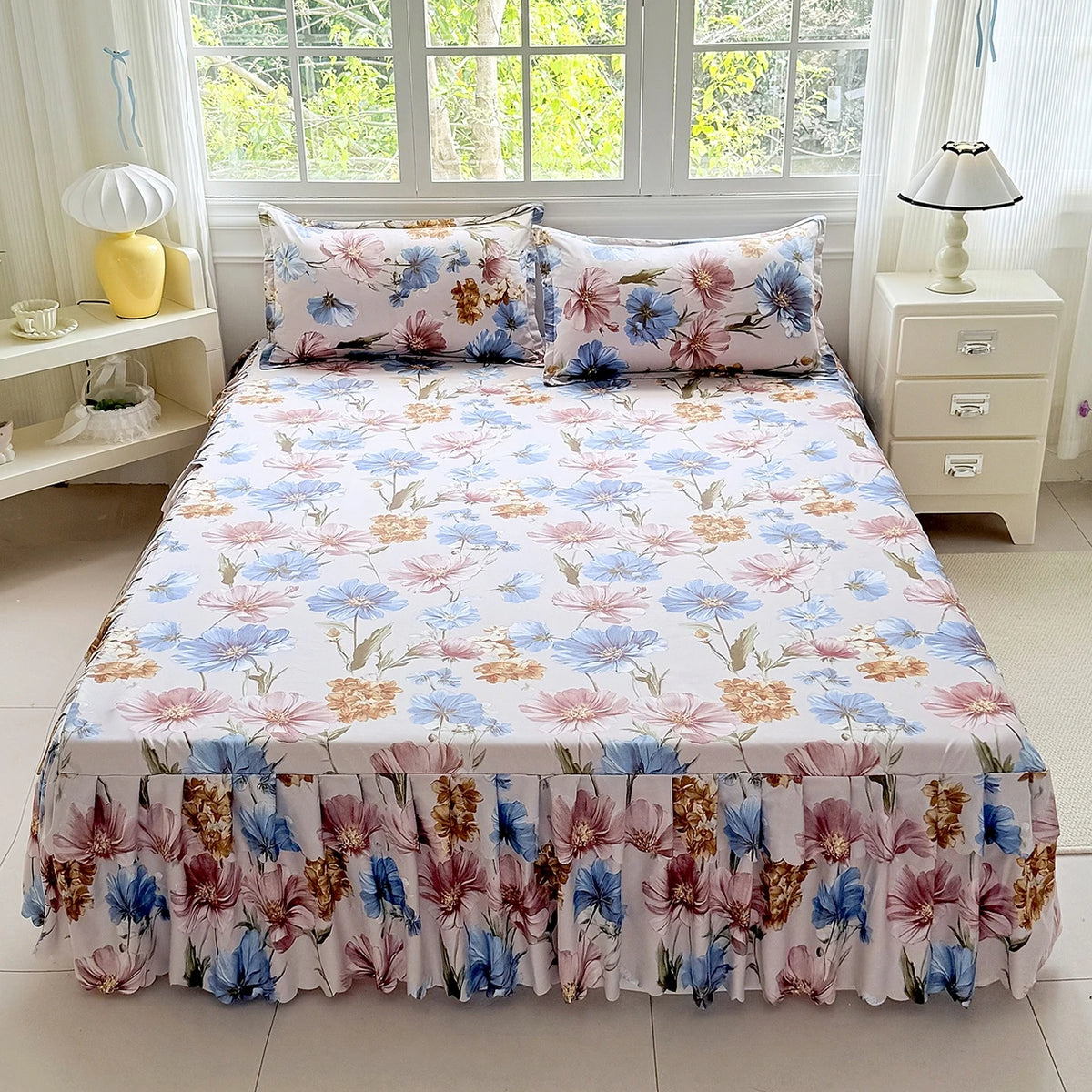 A floral print bed skirt and pillowcase set featuring pink, blue, and rust tones on a white background.