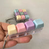 A hand holds a clear plastic case filled with colorful mini mechanical keyboard fidget pieces for stress relief.