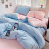 A light blue and pink cotton bedding set featuring a duvet cover, flat sheet, and pillows on a bed.