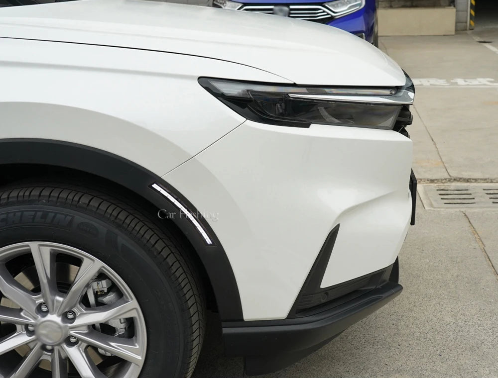 Front view of a white Honda CR-V showing the headlight and tire.