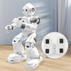 A white interactive dancing robot toy standing on a wooden surface with an inset showing its battery compartment.