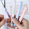A hand holds several mini pen-shaped scissors and cutters in various pastel colors against a blurred background.