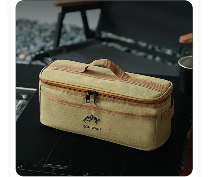 A beige portable storage bag for camping tableware with a brown trim, resting on a dark surface.