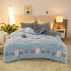 A light blue plush throw blanket with rabbit patterns is displayed on a bed, next to a lamp and framed art.