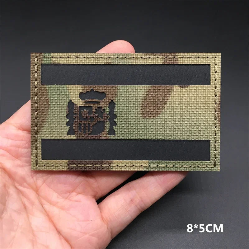 A rectangular tactical patch featuring a national flag design in camouflage colors with a crest and hook-and-loop backing.
