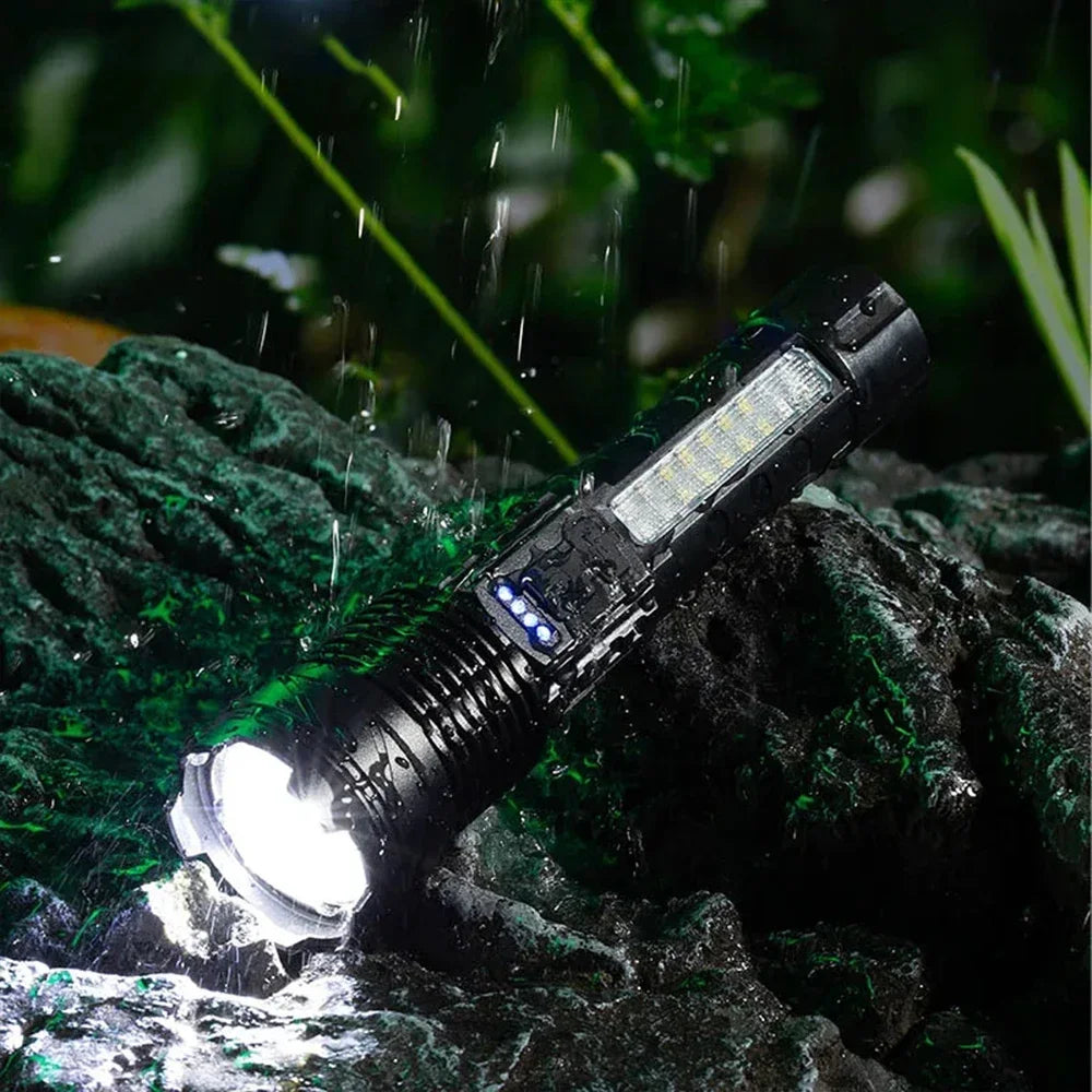 A black LED flashlight with a bright beam is shown shining on wet rocks in a dark, natural setting.
