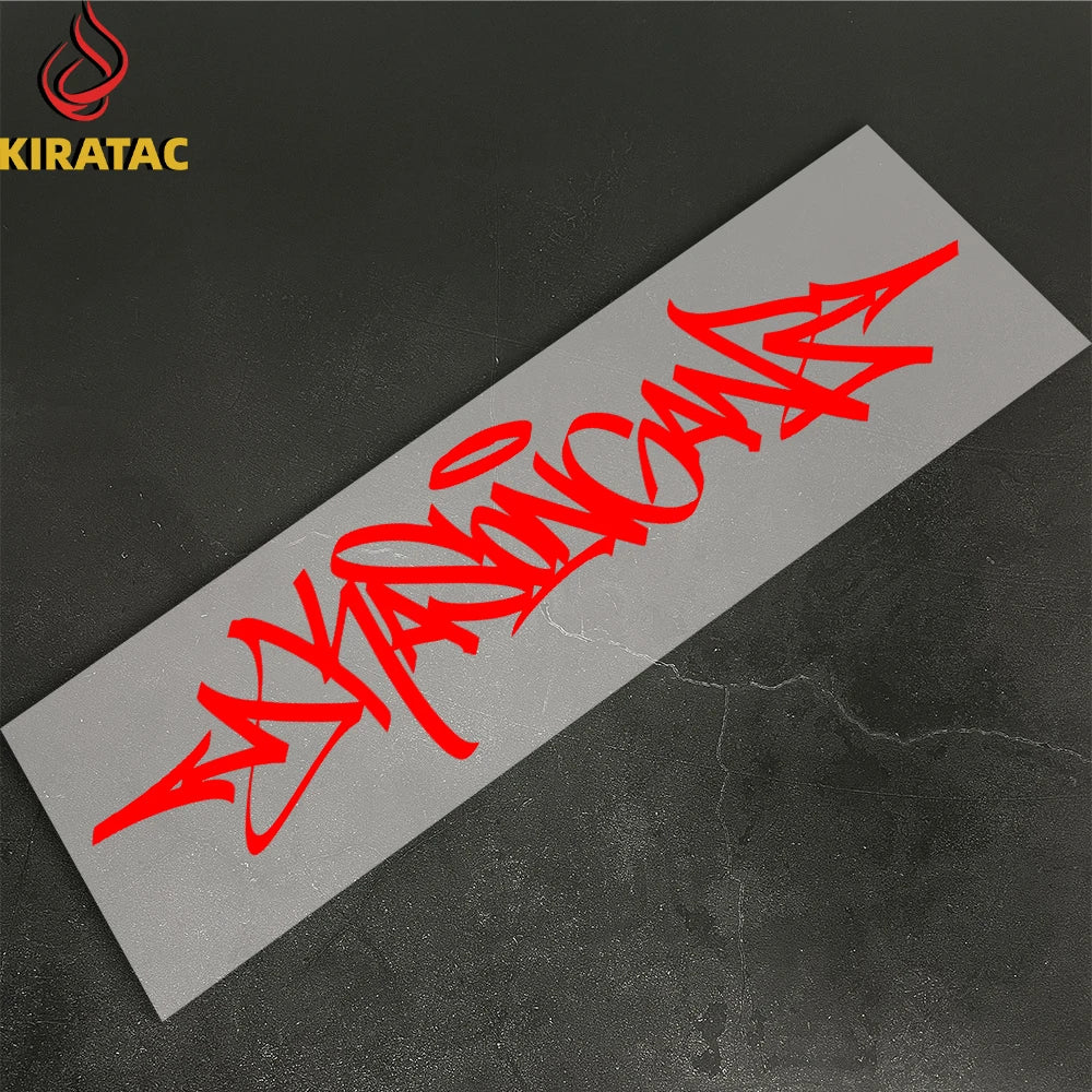Red wildstyle graffiti text on a gray sticker placed on a dark surface.