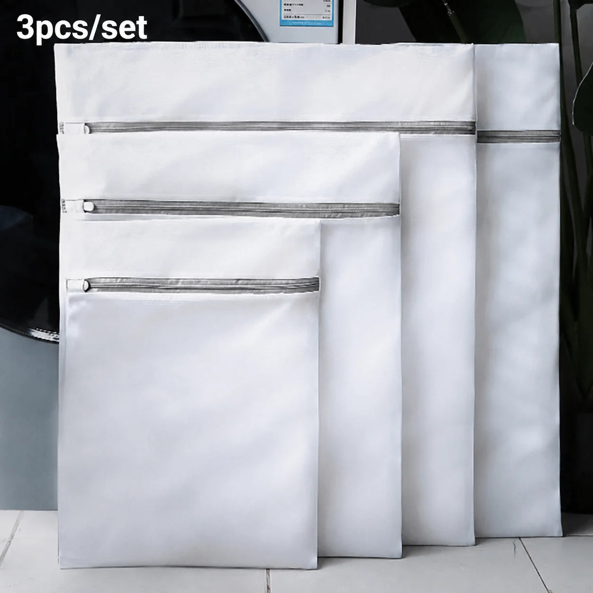 A set of three white mesh laundry bags with zippered tops displayed side by side.