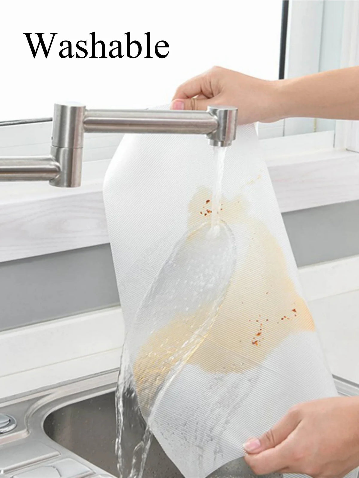 A hand is washing a white, mesh fridge shelf liner under a faucet.