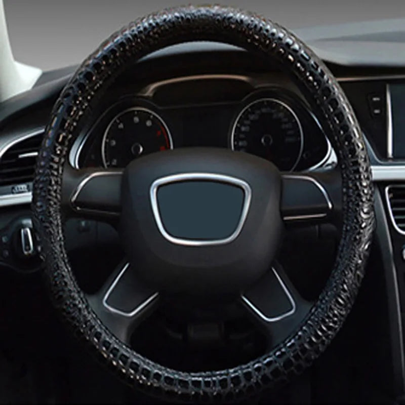 Close-up view of a black crocodile grain leather car steering wheel cover inside a vehicle