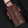 Portefeuille à fermeture éclair en cuir marron pour homme tenu dans la main sur fond noir.