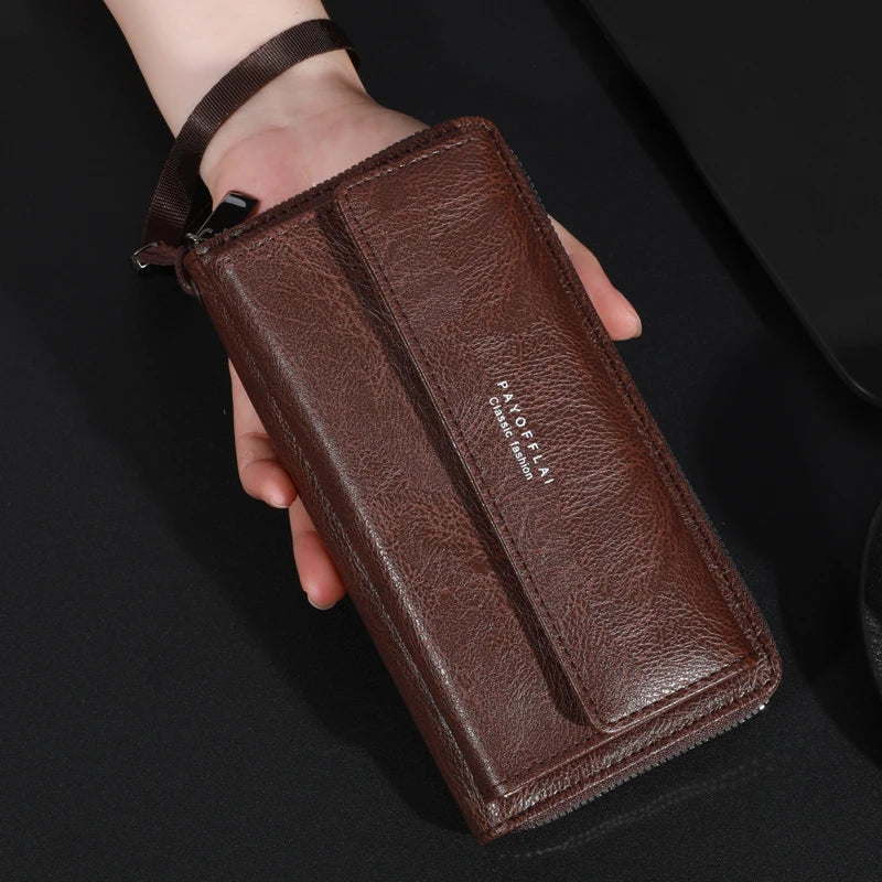 Portefeuille à fermeture éclair en cuir marron pour homme tenu dans la main sur fond noir.