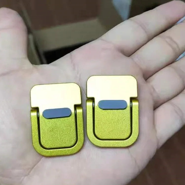 A hand holds a gold-colored aluminum portable laptop stand with adjustable legs.