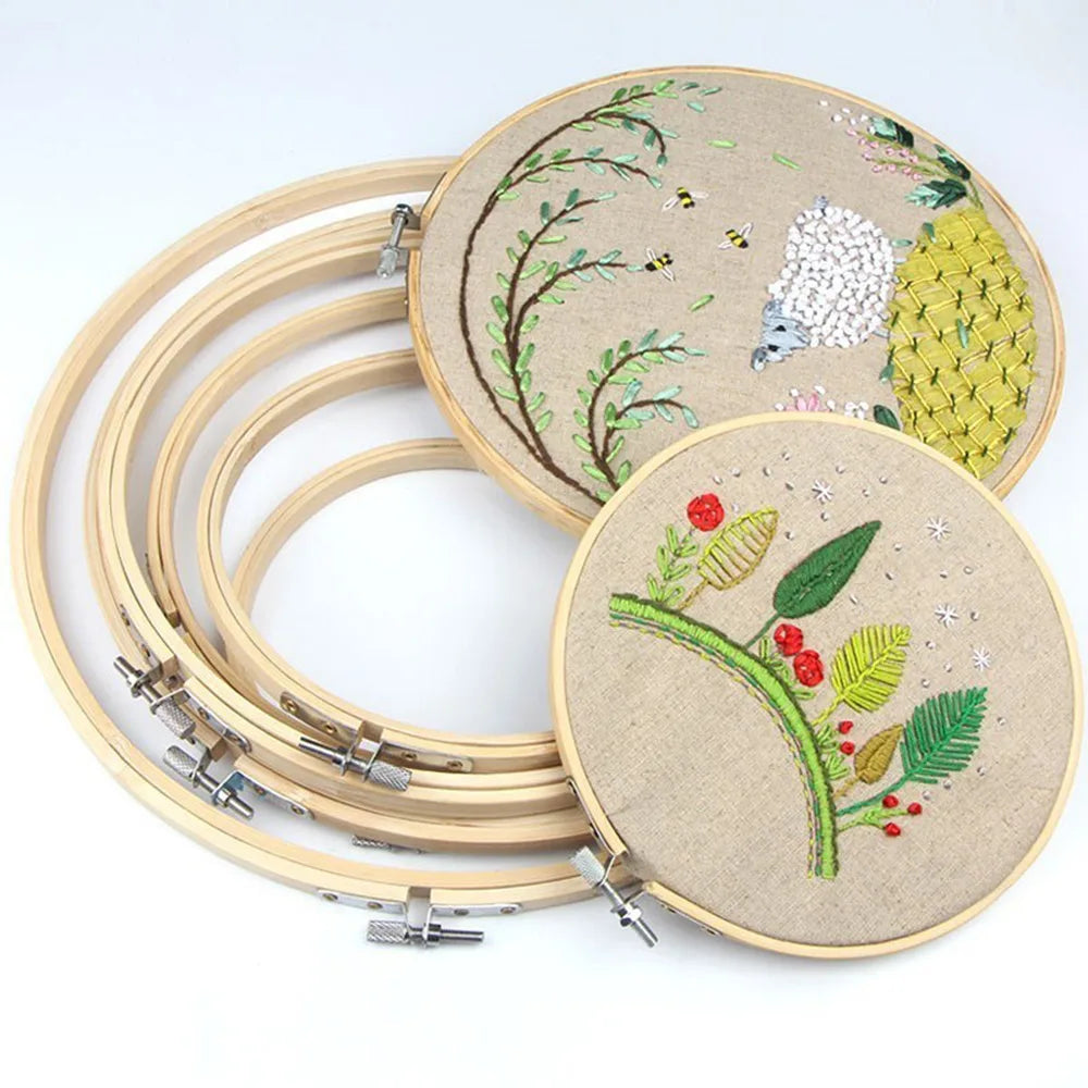 A set of bamboo embroidery hoops with adjustable screws and embroidery thread on a beige fabric.