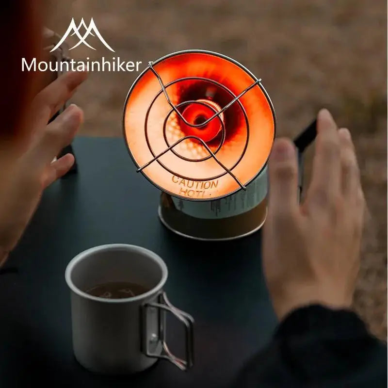 A hand holds a portable butane gas stove with a visible flame, set against a dark background.