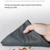 A hand is wiping oil stains off a gray cloth, demonstrating its strong cleaning power.