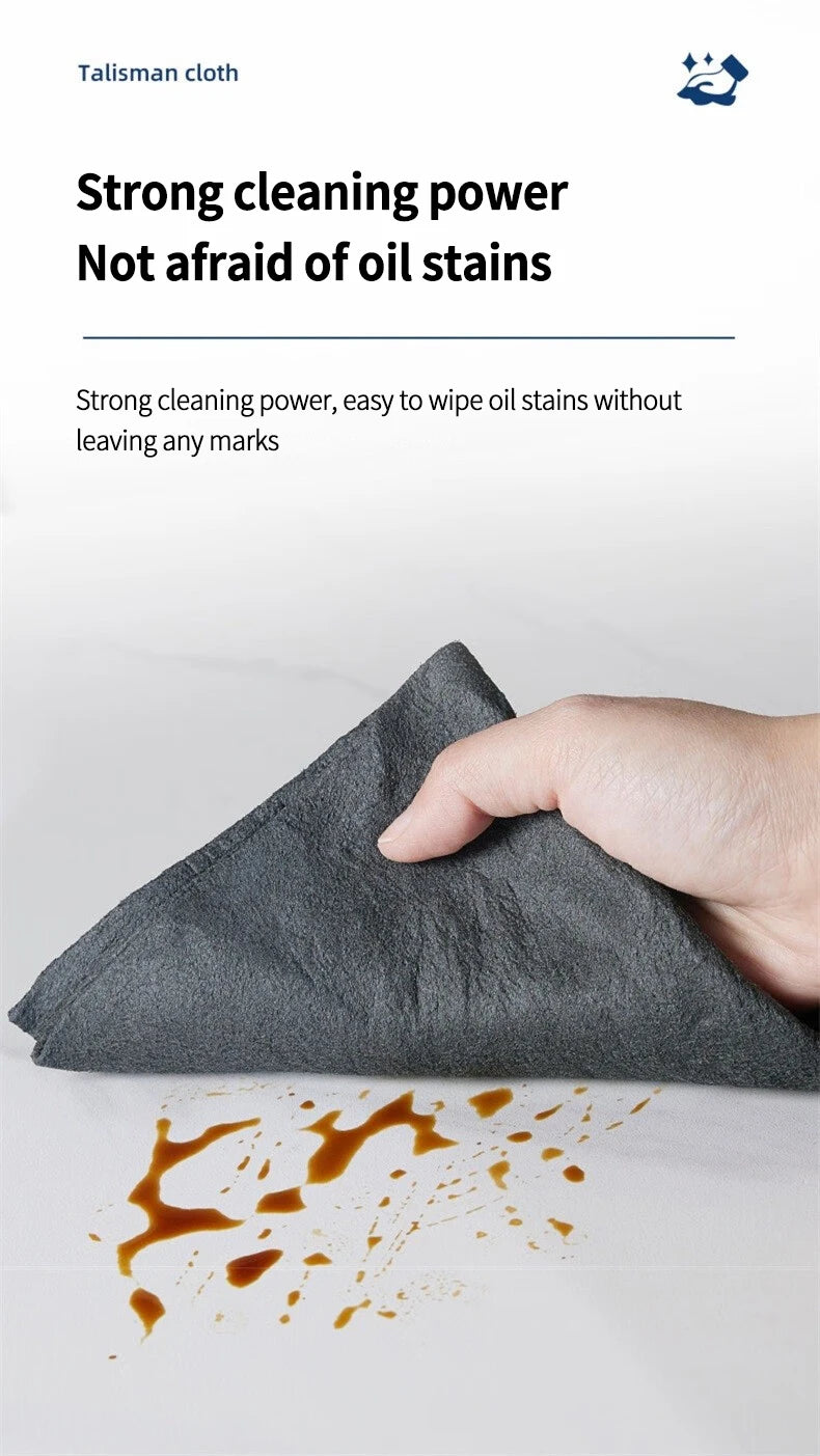 A hand is wiping oil stains off a gray cloth, demonstrating its strong cleaning power.