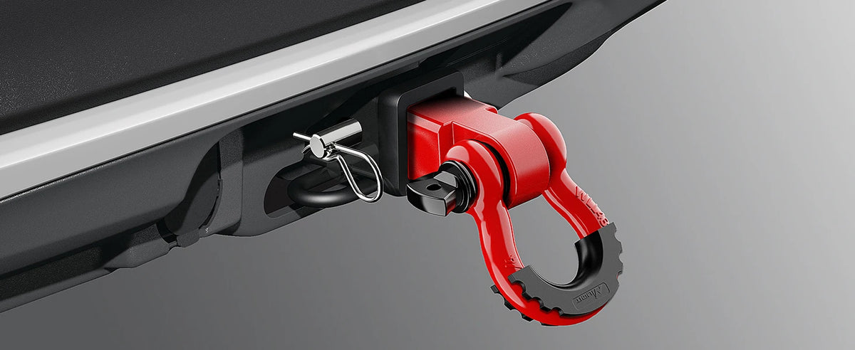 A close-up view of a red heavy-duty shackle hitch receiver with a D-ring and trailer pin mounted on a silver vehicle frame.