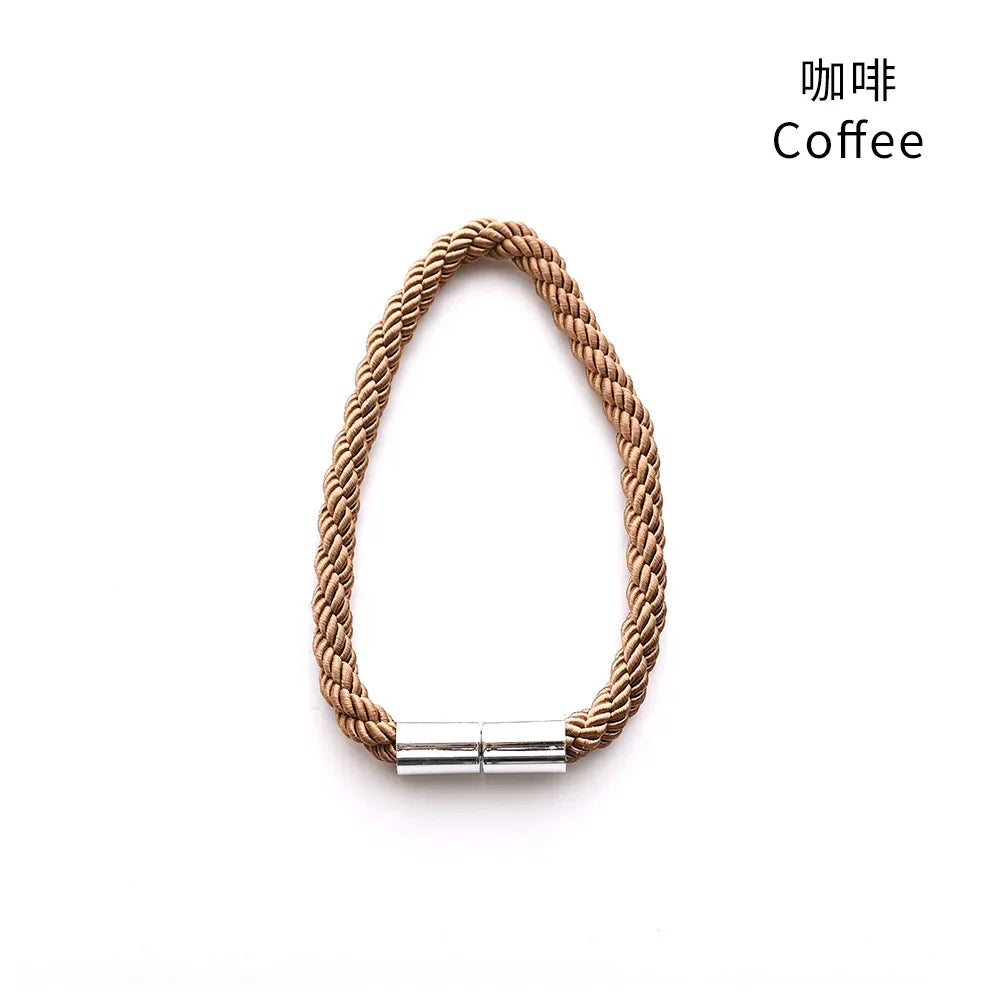 A close-up of a natural beige rope tieback with a silver magnetic clasp.