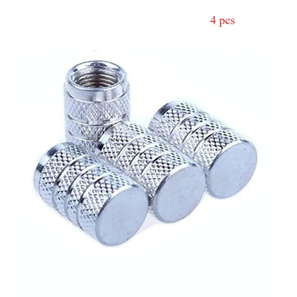 A set of four knurled aluminum tire valve caps with threaded tops shown against a white background.