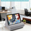 A gray adjustable comfort tablet and phone stand pillow resting on a white table in an office setting.