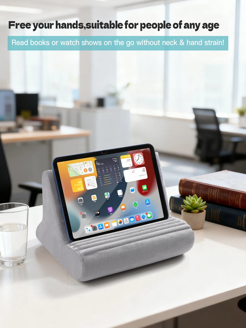A gray adjustable comfort tablet and phone stand pillow resting on a white table in an office setting.
