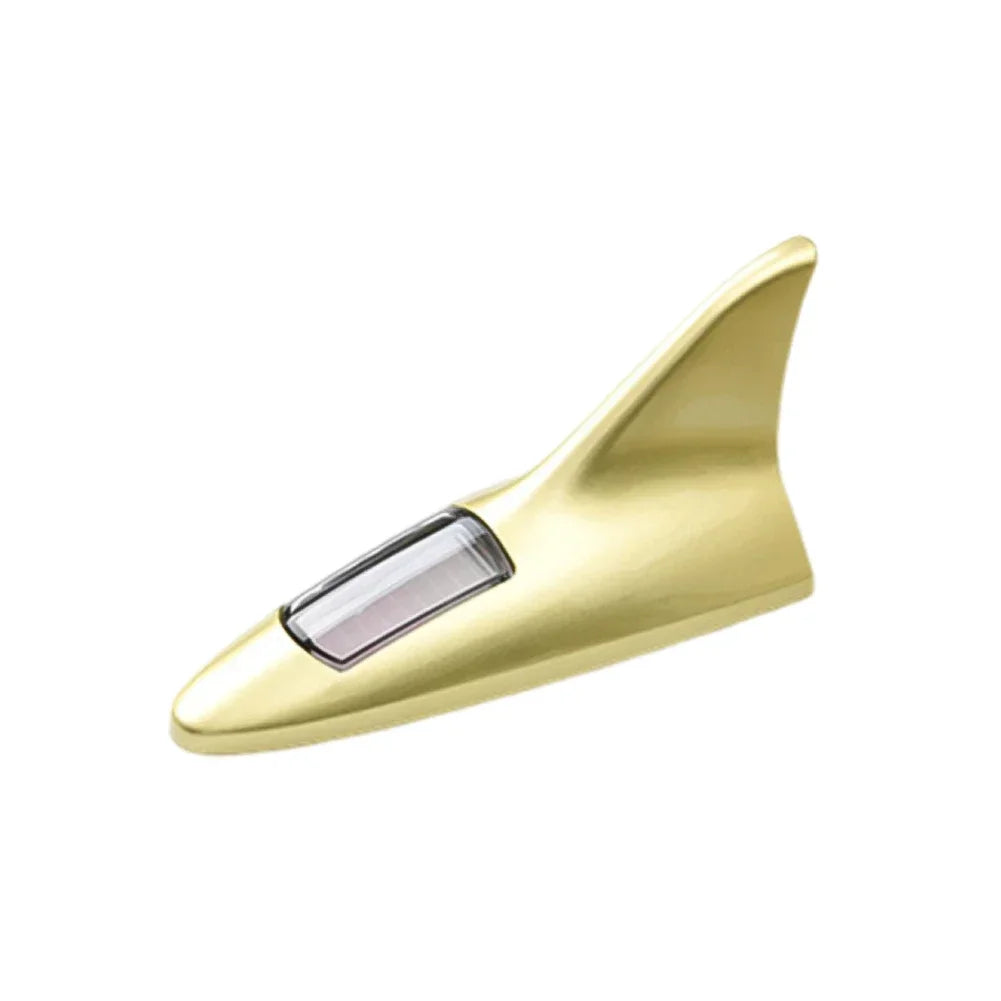 A gold-colored solar-powered shark fin antenna with a clear protective lens and LED safety light.