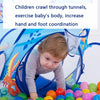 A toddler crawls through a blue ball pit play tent with an attached tunnel, surrounded by colorful balls.