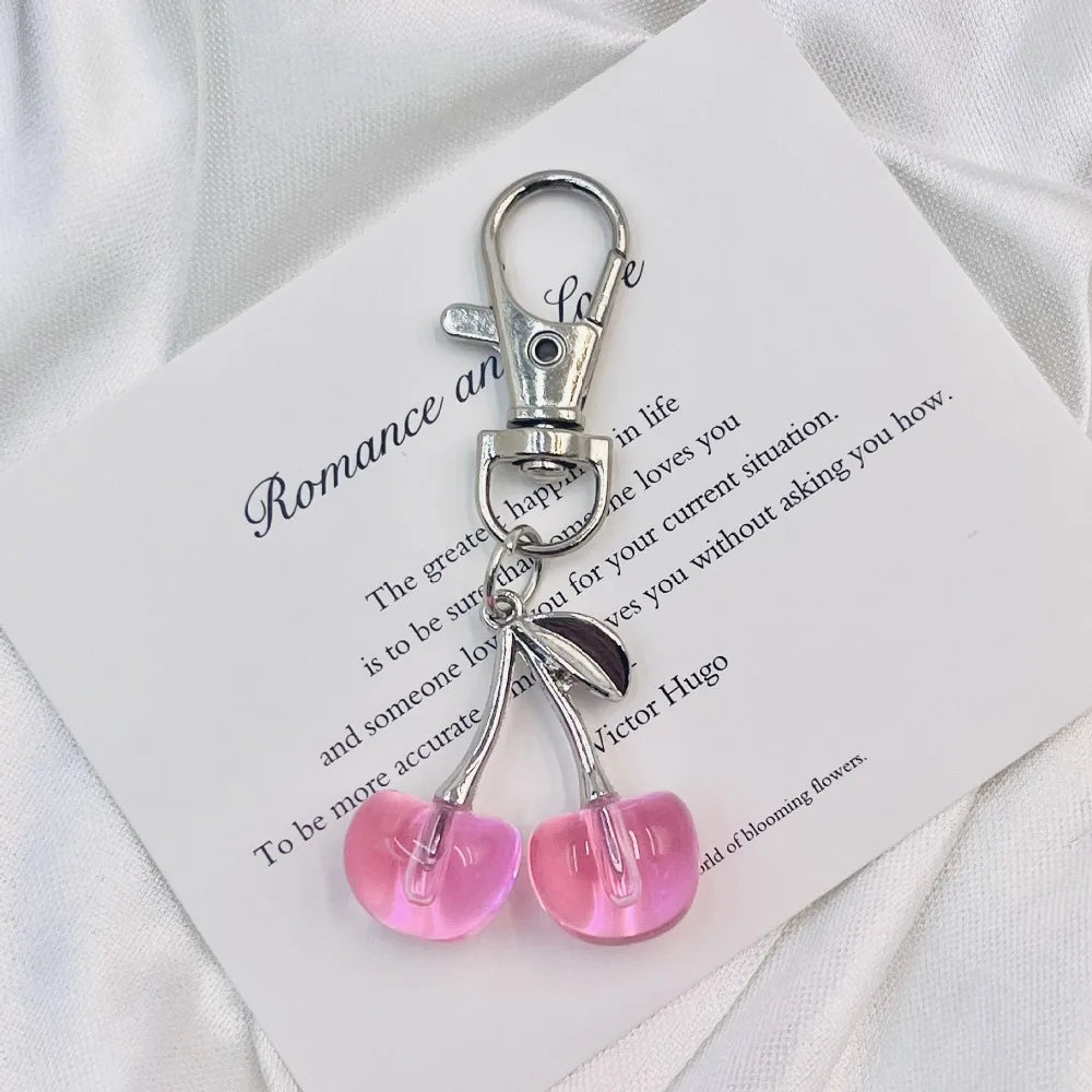 Clé portail en forme de cerise argentée scintillante attachée à une carte blanche avec un texte romantique.