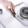 A hand is using a dark cleaning sponge to wipe a surface on an Emery cleaning sponge.