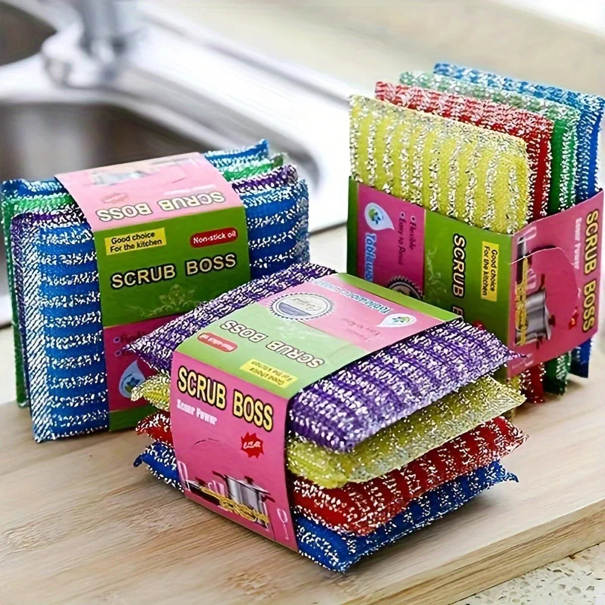 A collection of colorful double-sided kitchen scouring sponges in various patterns and colors stacked on a wooden surface.