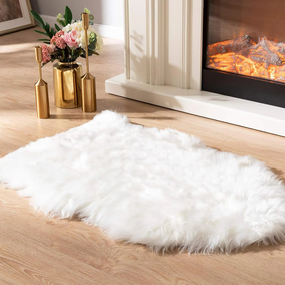 Un tapis en fausse fourrure blanche et hirsute sur un plancher de bois clair devant une cheminée
