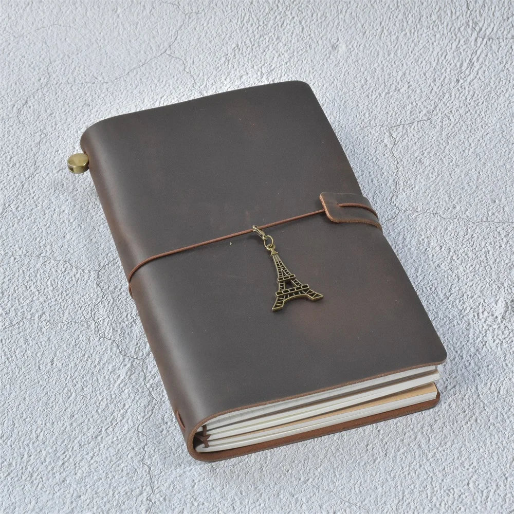 A brown leather refillable journal with a brass-colored leather tie and stacked white paper pages.
