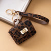 A brown leopard print PU leather keychain mini wallet with a gold-tone clasp resting on a beige surface.