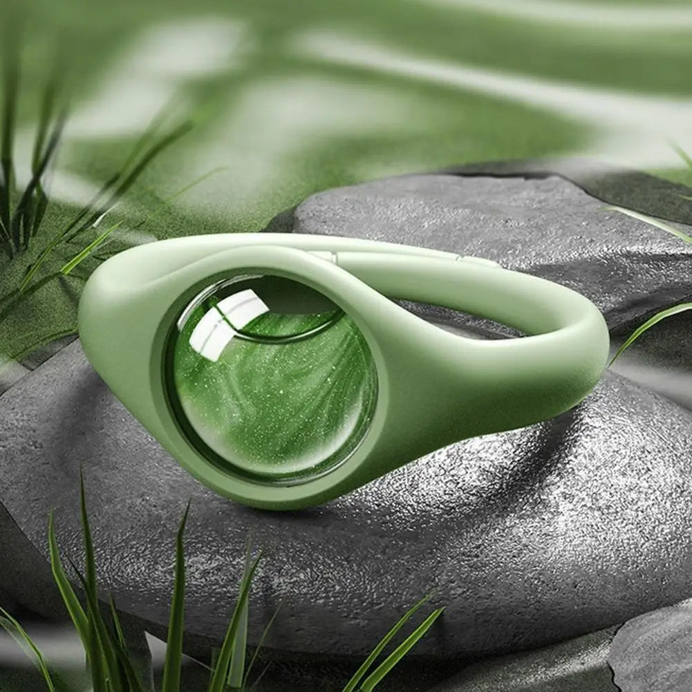 A light green natural mosquito repellent wristband resting on a dark gray stone amidst green foliage.