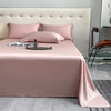 A pink luxury bamboo flat sheet is displayed on a bed with matching pillows and a watch.