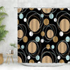 Geometric black and white fabric shower curtain with gold accents hanging in a bathroom.