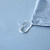 Light blue quilted duvet cover set with white ties lying on a light blue surface.